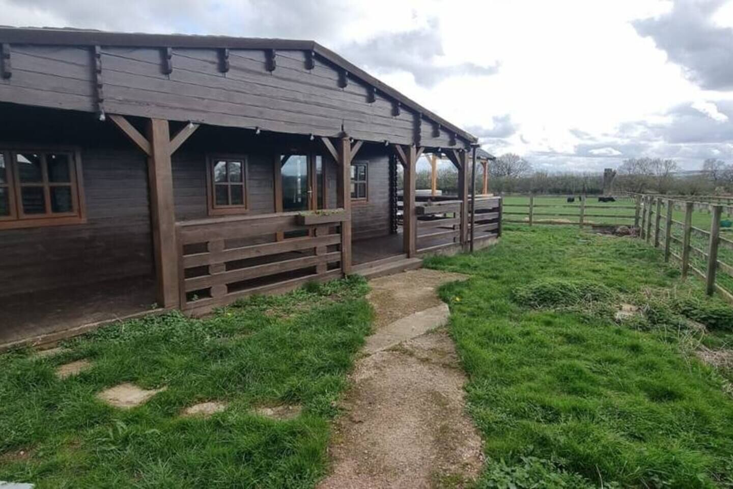 A wooden building with a porch and a dirt path leading to it.