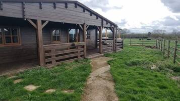 A wooden building with a porch and a dirt path leading to it.