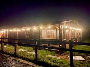 Ein rustikales Holzgebäude mit einer großen Tür und Fenstern, umzäunt.
