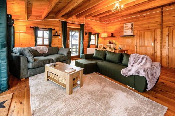 A cozy log cabin interior with a sectional sofa, a coffee table, and a fireplace.