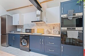 A modern kitchen with stainless steel appliances, a built-in washing machine, and a microwave.