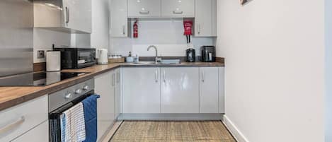 A modern kitchen with stainless steel appliances, white cabinetry, and a small island with a sink.