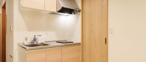 A compact kitchen with a built-in stove, a sink, and wooden cabinets.