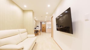 Ein modernes Interieur mit einer Couch, einem an der Wand montierten Flachbildfernseher und einer Küchenzeile im Hintergrund.