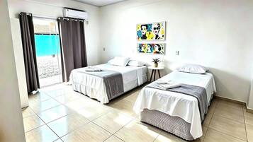 A hotel room with two beds, a small table, and artwork on the wall.