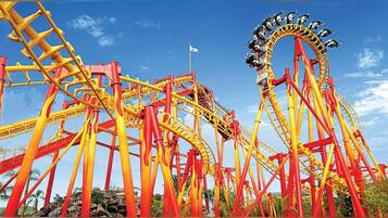 A roller coaster with a steep drop and a loop, set against a clear blue sky.