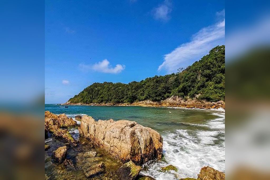 A coastal landscape with rocky terrain and a clear blue sky.