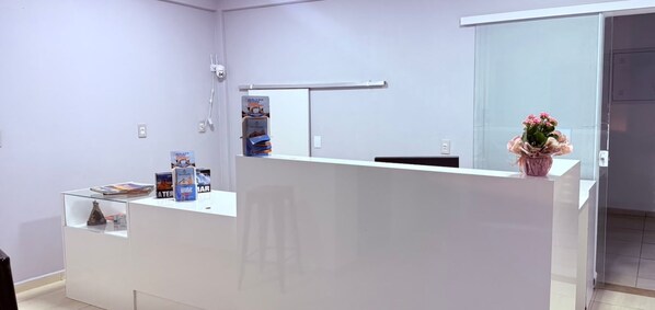 A reception desk with a glass partition, a security camera, and a potted plant.