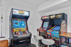 A room with arcade gaming machines, including a Capcom cabinet and a Sega console.