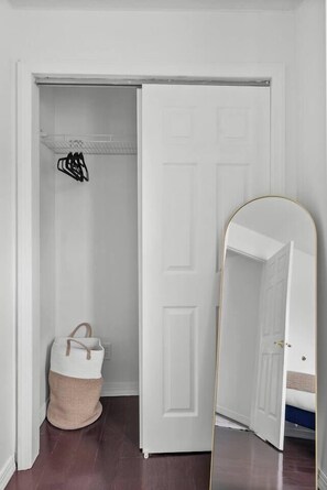 A room with a white door, a mirror, and a woven basket.