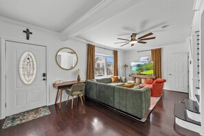 A modern living room with a sofa, a television, and a ceiling fan.