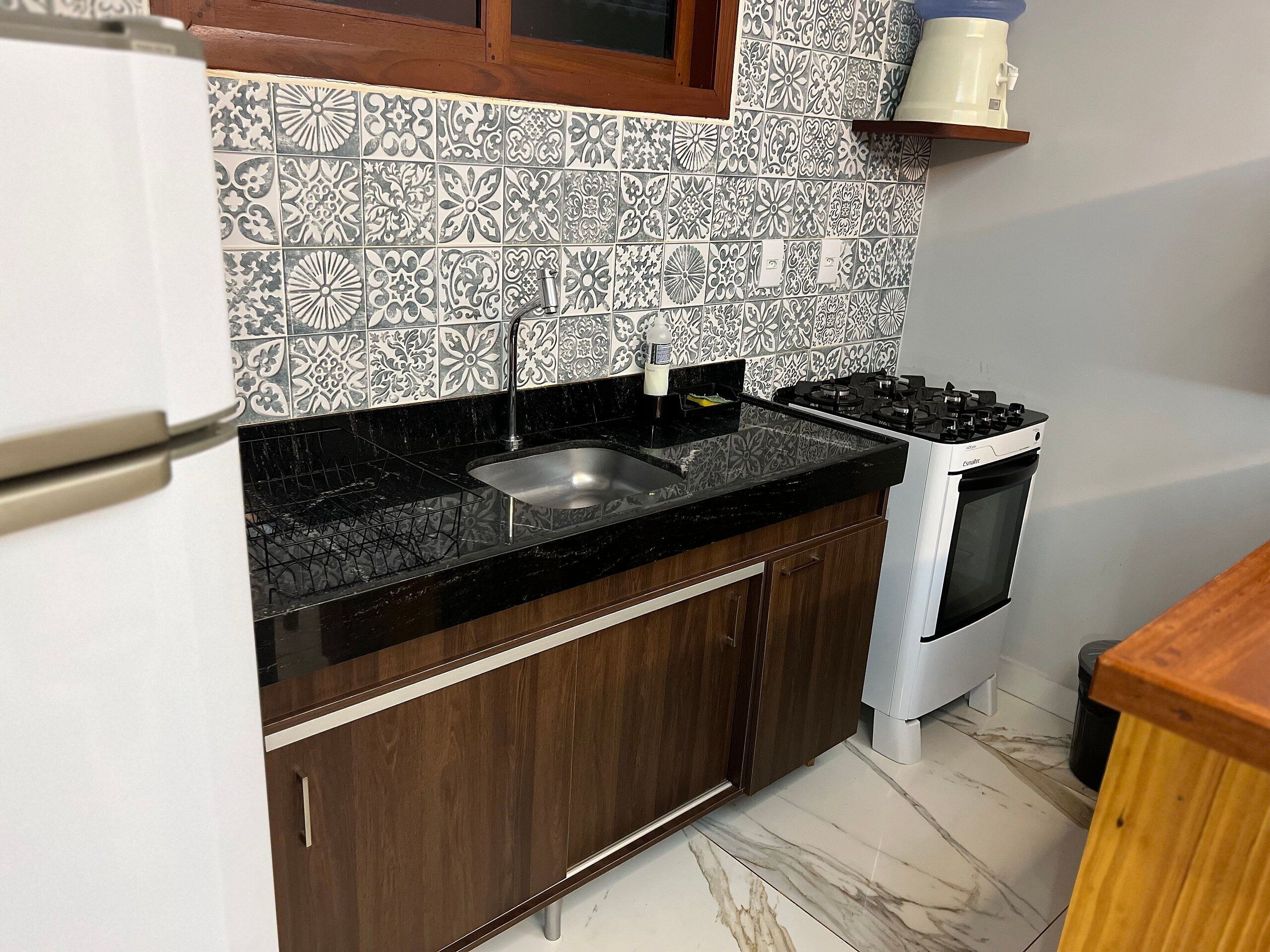 A kitchen with a black countertop, stainless steel sink, and a white stove.