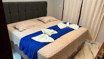 A bed with a quilted headboard, a blue bedspread, and two towels arranged in bows.