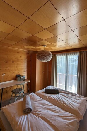Ein Zimmer mit zwei Betten, einem Schreibtisch und einer Hängelampe.