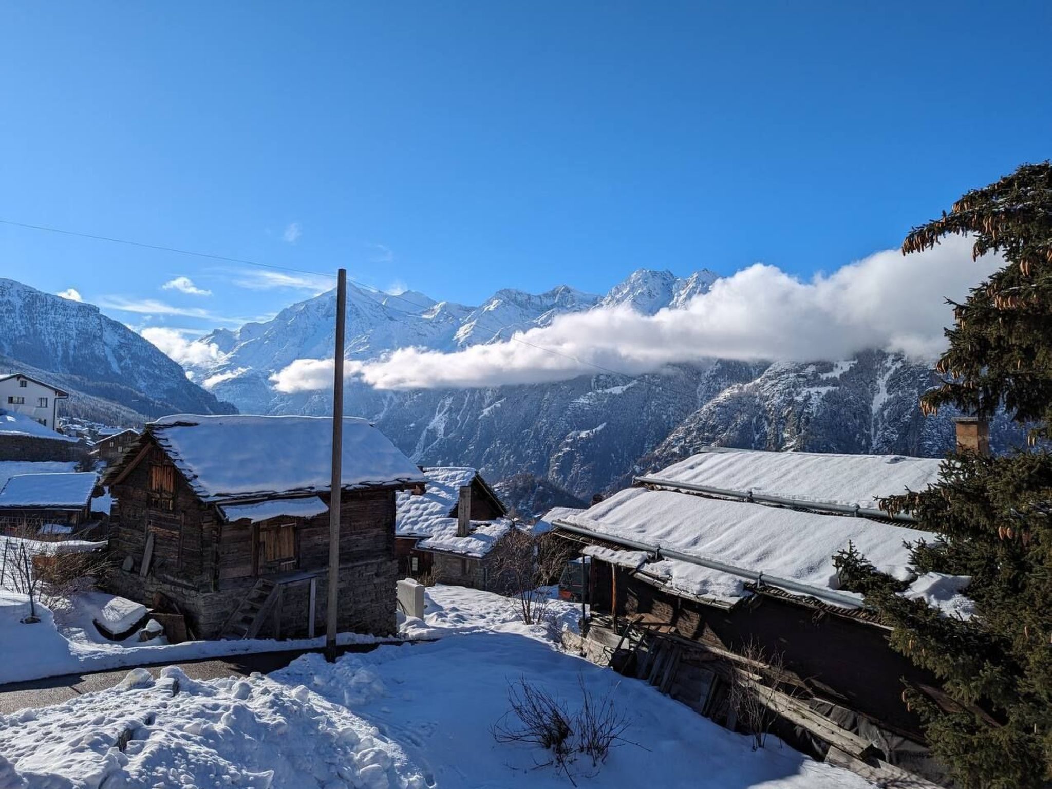 Een besneeuwd dorp met traditionele houten huizen en een berg op de achtergrond.