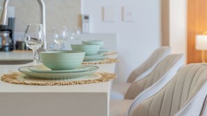 Un comedor con una fila de mesas, cada una con un tazón verde y un vaso sobre un posavasos tejido.