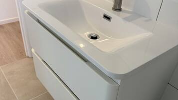 A modern bathroom with a white sink, a mirror, and a towel rack.
