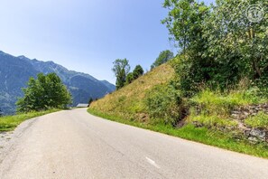 A curving mountain road with a clear sky and lush greenery on both sides. - The Bisanne Mill: The Beaufortain Balcony (VILLARD SUR DORON)