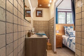 A compact room with a wooden vanity, a bed with patterned bedding, and a window with a view. - The Bisanne Mill: The Beaufortain Balcony (VILLARD SUR DORON)
