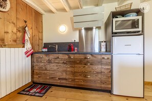 Eine Küche mit Holztischplatte, Edelstahlgeräten und einem weißen Kühlschrank.