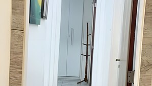 Ein Korridor mit weißen Wänden, einem Marmorboden und einer Tür am Ende.