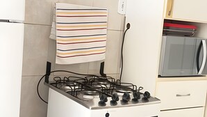Eine Küche mit einem Gasherd, einem gestreiften Handtuch an der Wand und einer Mikrowelle.