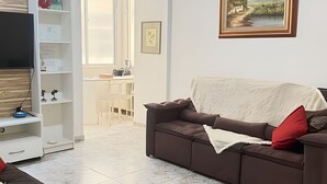 A living room with a sofa, a coffee table, a TV, and a painting on the wall.