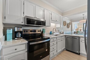 A modern kitchen with white cabinetry, stainless steel appliances, and a dishwasher. - Luxury Oceanfront 3BR | Stunning Beach Views (North Myrtle Beach)