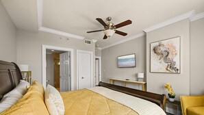 A hotel room with a bed, a ceiling fan, a television, and artwork on the wall. - 3BR Harborfront Condo - Pool, Hot Tub, Bay Shuttle (Destin)