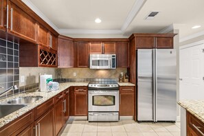 A kitchen with wooden cabinets, a stainless steel refrigerator, a microwave, and an oven. - 3BR Harborfront Condo - Pool, Hot Tub, Bay Shuttle (Destin)