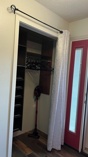 Une pièce avec un placard, un aspirateur et une porte avec une fenêtre.