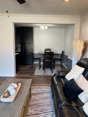Un salon moderne avec un canapé en cuir, une table basse en bois et un coin repas comprenant une table et des chaises.