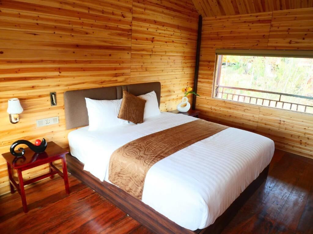 Una habitación con paneles de madera, una cama, lámparas de noche y un ventanal.
