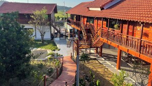 Un edificio de madera con techo de tejas rojas, una escalera de madera y un jardín.