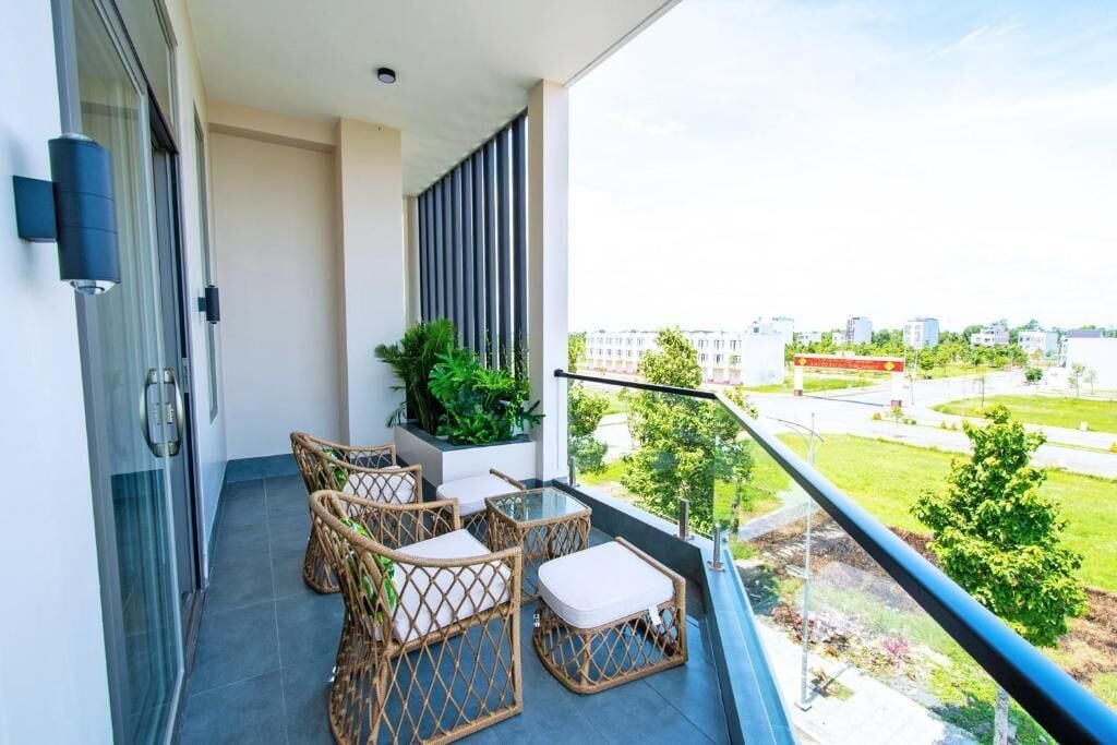Un balcon avec des meubles en osier, une porte vitrée et une vue sur le paysage urbain.