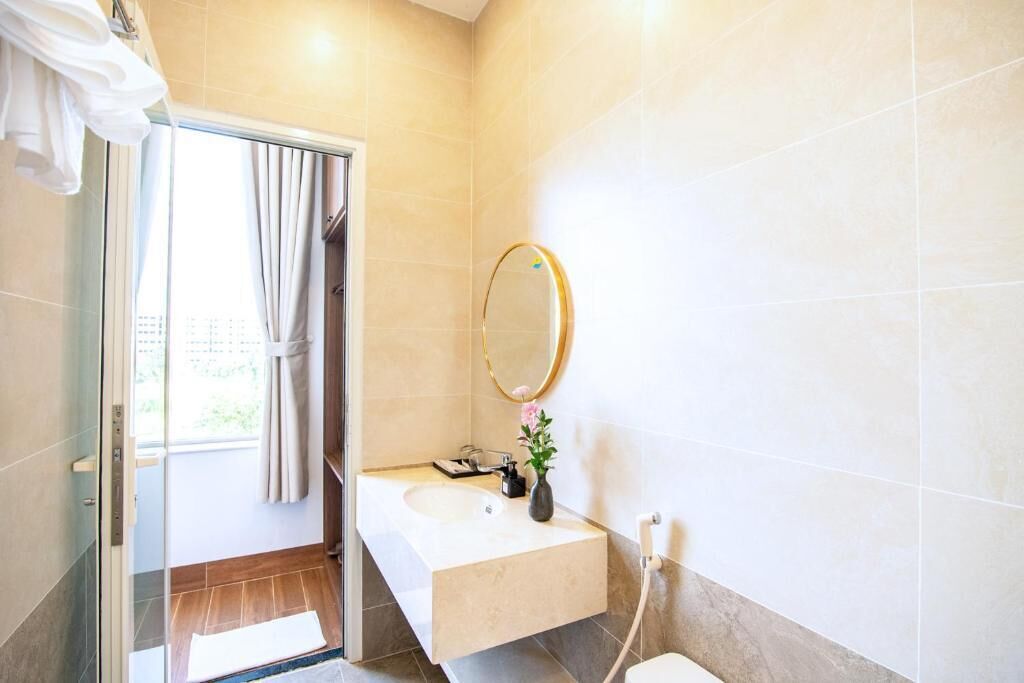 Un baño con mampara de vidrio, un lavamanos con espejo y un perchero para toallas.