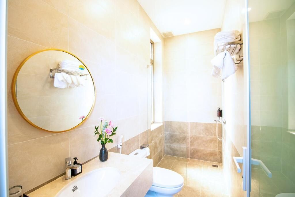 A modern bathroom with a round mirror, a sink, a toilet, and a shower area.