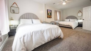 Habitación de hotel con dos camas, un ventilador de techo, un cuadro y una puerta.