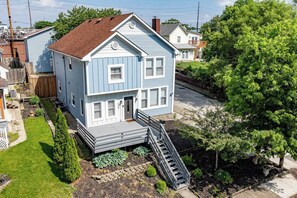 A two-story house with a front porch and a staircase leading to the entrance. - 10 Min to Lucas Oil~Walk to Mass Ave~Hot Tub (Indianapolis)