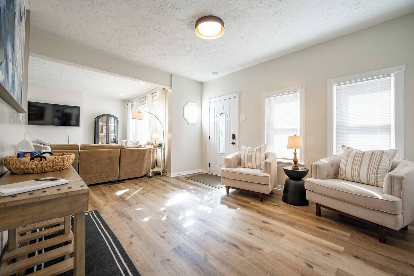 A spacious living area with a wooden floor, a sofa, a coffee table, and a television mounted on the wall.