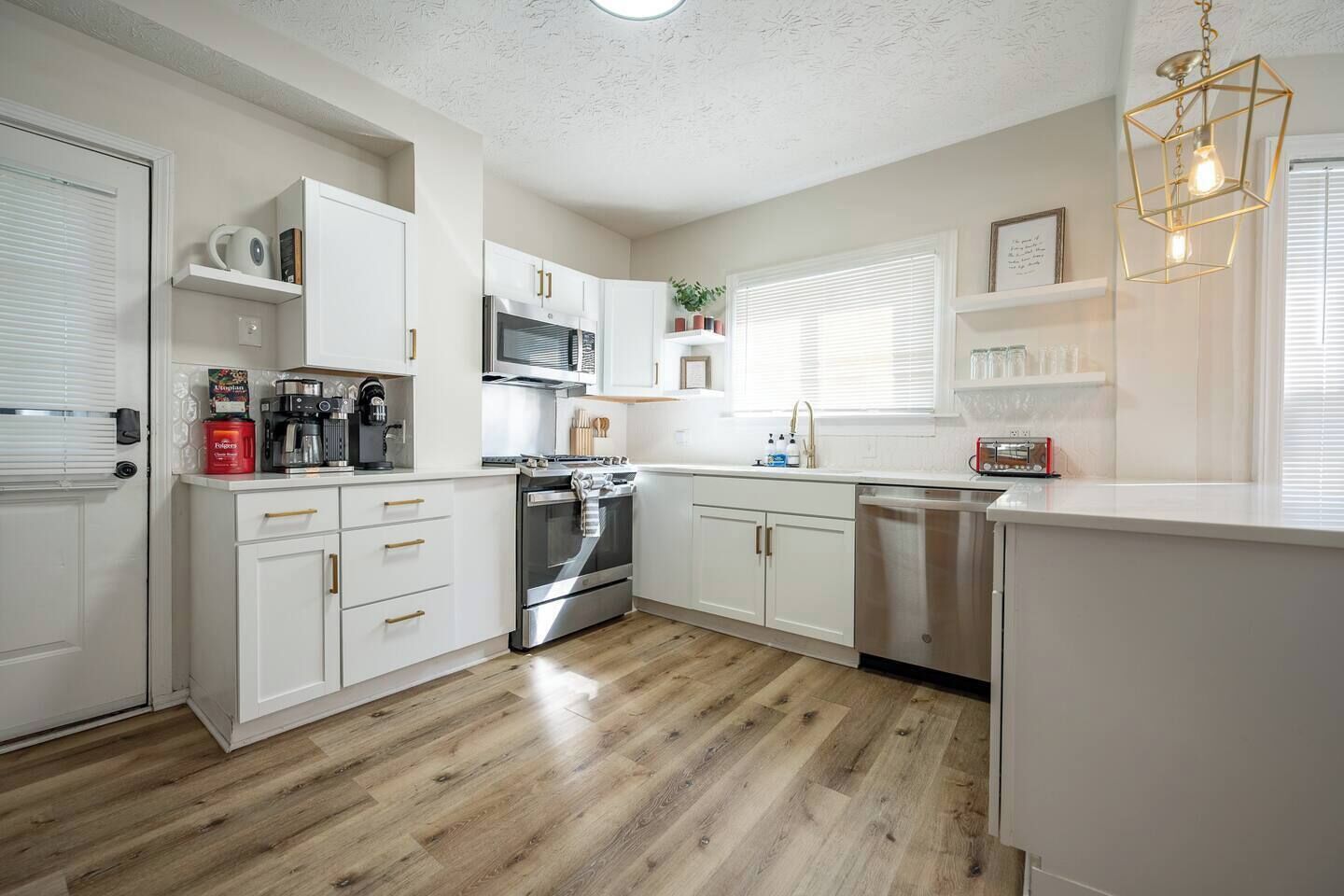 A modern kitchen with white cabinetry, stainless steel appliances, and a wooden floor.