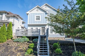 A two-story house with a front porch and a wooden staircase leading to the entrance. - 10 Min to Lucas Oil~Walk to Mass Ave~Hot Tub (Indianapolis)
