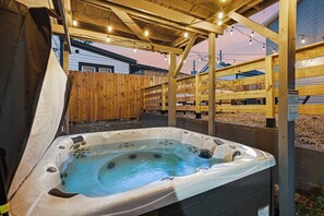 A hot tub under a wooden pergola with string lights, surrounded by wooden fences. - 10 Min to Lucas Oil~Walk to Mass Ave~Hot Tub (Indianapolis)