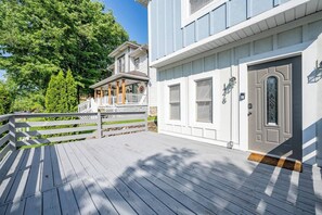 A wooden deck with a white railing, a grey door with a glass panel, and a mailbox. - 10 Min to Lucas Oil~Walk to Mass Ave~Hot Tub (Indianapolis)