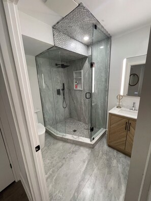 A modern bathroom with a glass-enclosed shower, a wooden vanity, and a marble floor. - Spacious private bedroom with ensuite and living room with separate entrance (Oshawa)