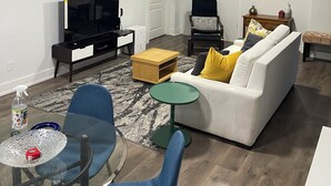 Moderni olohuone, jossa on sohva, televisio, sohvapöytä ja tuoleja.