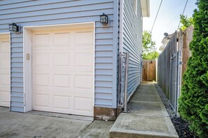 A residential garage with a white door, adjacent to a house with light blue siding and a wooden fence. - Quaint Downtown Indy~Walk to Mass Ave~Nearby Park (Indianapolis)