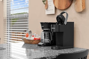 A kitchen counter with a coffee maker, a bowl, and a bag of coffee pods. - The Lazy Beaver Lodge - Hot Tub (Hollister)