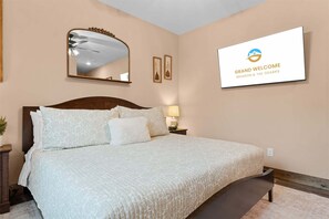Ein Schlafzimmer mit einem großen Bett, einem Deckenventilator, einem an der Wand befestigten Spiegel und einem gerahmten Willkommensschild.