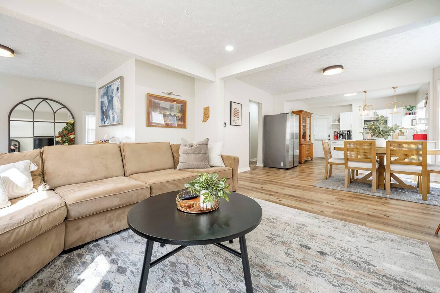 A modern living room with a sofa, a coffee table, and a dining area with wooden chairs and a table.
